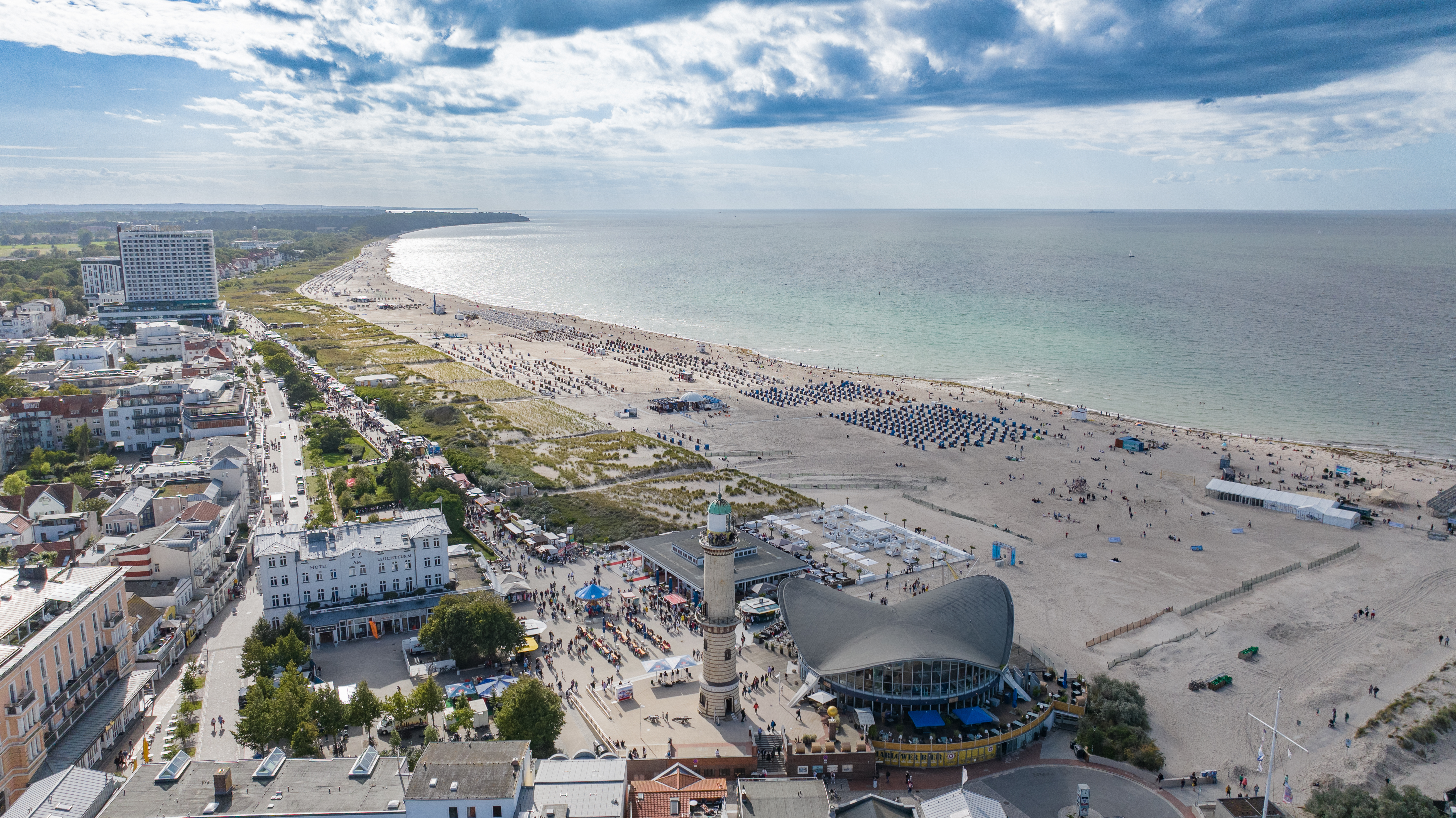 Warnemünder Strand und Promenade zur Hanse Sail. Historischer Leuchtturm im Vordergrund