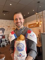 Felix Kühl von der Stadtbäckerei Kühl hält eine Tüte voller Brötchen in der Hand