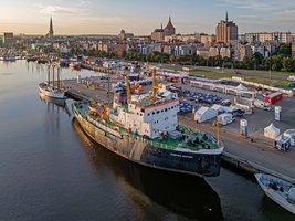 Großes Schiff mit schwarzen Rumpf, Weiß orangenen Aufbauten und grünen Deck
