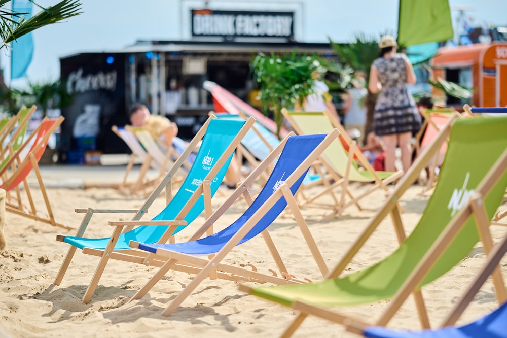 Bunte Strandstühle mit NDR1 Schriftzug stehen auf Sand. 