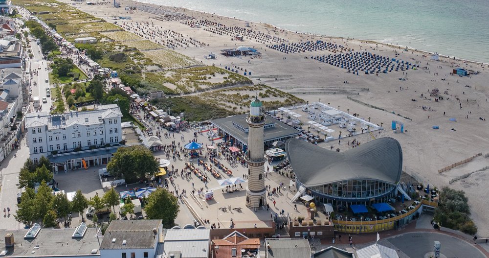 Warnemünder Strand und Promenade zur Hanse Sail. Historischer Leuchtturm im Vordergrund